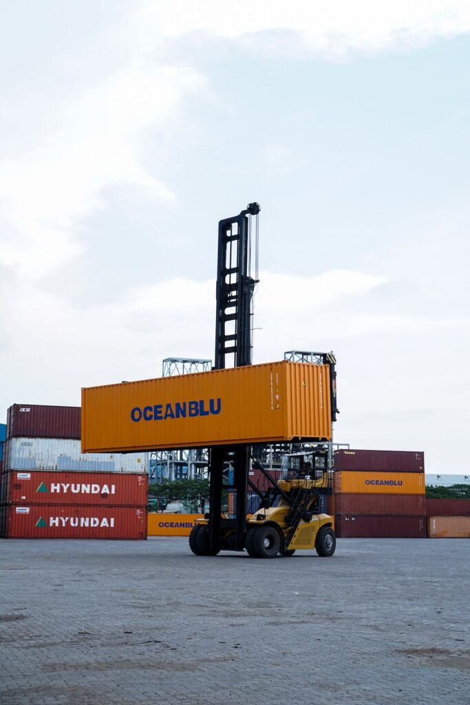 A forklift operated by a single person lifting a large container.